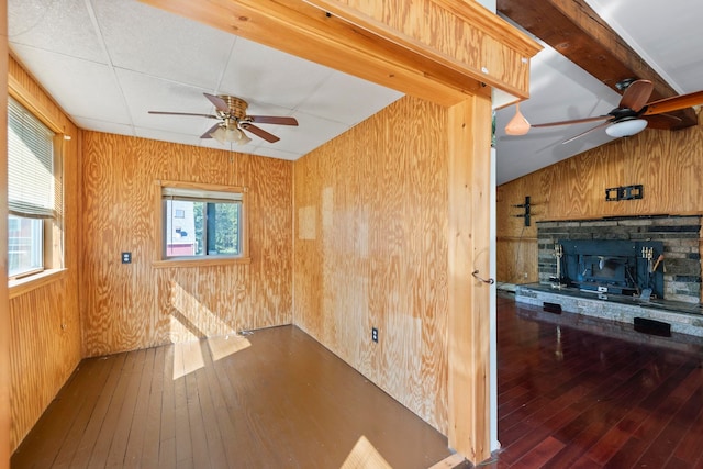 unfurnished room featuring a healthy amount of sunlight, ceiling fan, and a stone fireplace