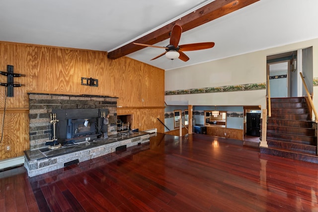 living room with wooden walls, ceiling fan, a stone fireplace, lofted ceiling with beams, and hardwood / wood-style flooring