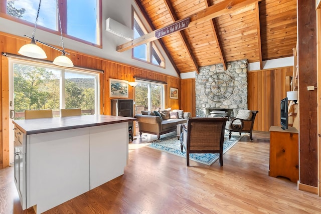 living room with beamed ceiling, wood ceiling, wooden walls, a stone fireplace, and high vaulted ceiling