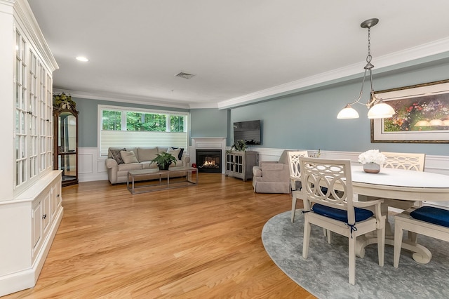 dining room with crown molding and light hardwood / wood-style floors