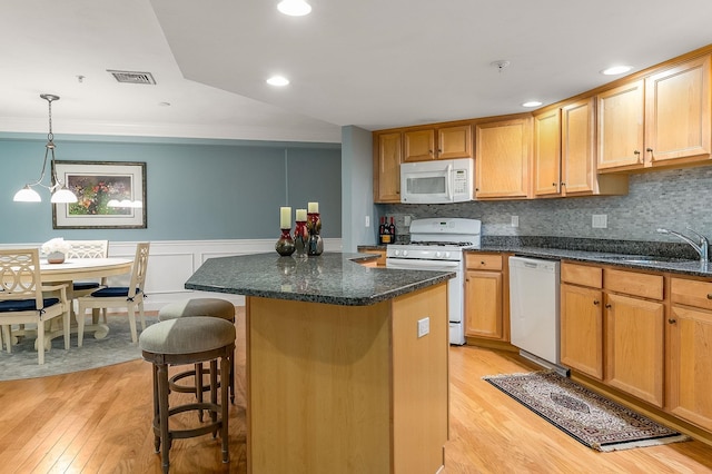 kitchen featuring light wood-type flooring, white appliances, decorative light fixtures, and sink