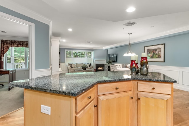 kitchen featuring light wood-type flooring, a kitchen island, crown molding, and a healthy amount of sunlight