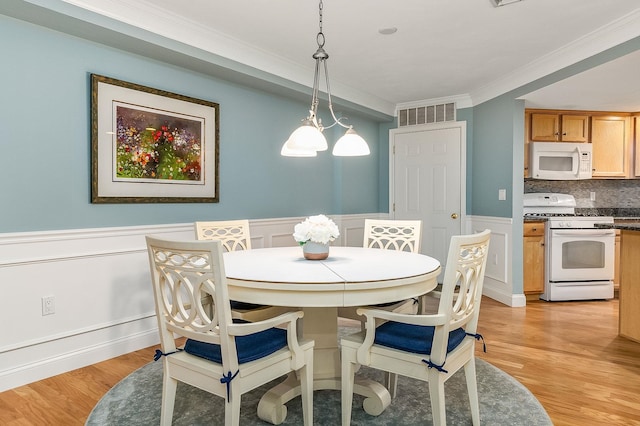 dining area with crown molding and light hardwood / wood-style flooring