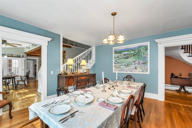 dining space featuring ceiling fan with notable chandelier and wood-type flooring