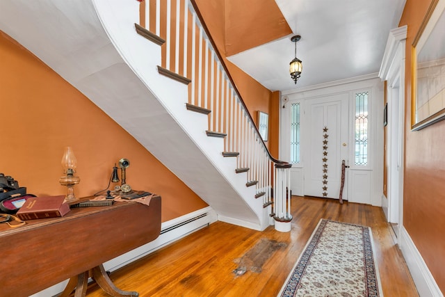 foyer entrance featuring ornamental molding, baseboard heating, and hardwood / wood-style floors