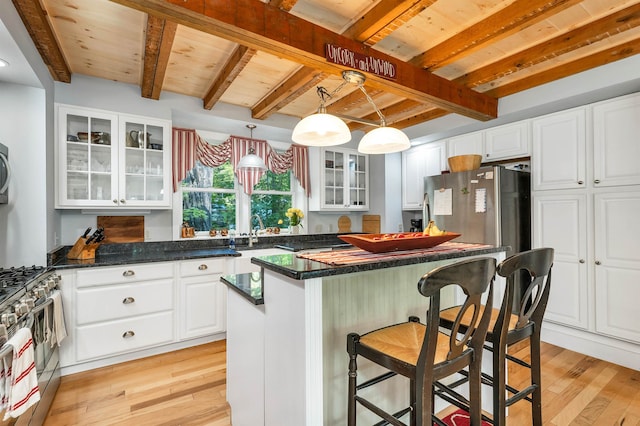 kitchen featuring decorative light fixtures, a center island, stainless steel appliances, and white cabinets