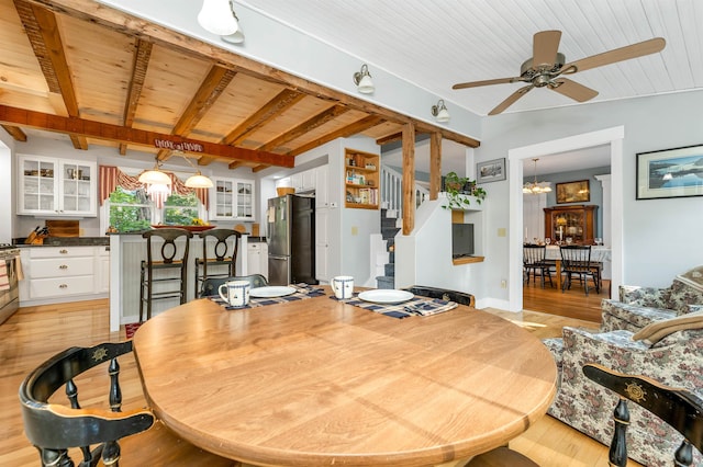 dining area featuring ceiling fan with notable chandelier, light wood-type flooring, lofted ceiling with beams, and wood ceiling