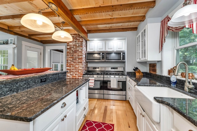 kitchen with stainless steel appliances, hanging light fixtures, plenty of natural light, and white cabinetry