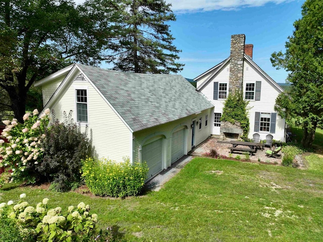 back of property featuring a garage and a yard