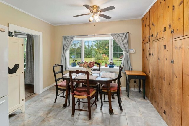 dining space with ceiling fan, light tile patterned floors, and crown molding