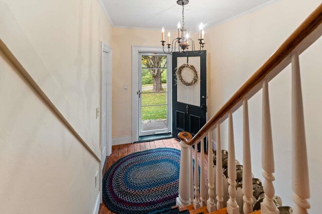 foyer with light hardwood / wood-style flooring, an inviting chandelier, and crown molding