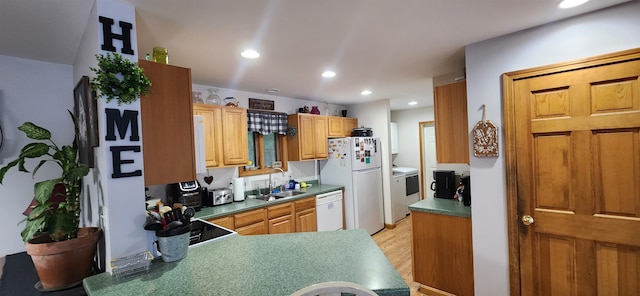 kitchen with white appliances, washer / dryer, light wood-type flooring, and sink