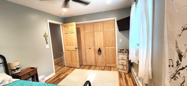 bedroom featuring baseboard heating, ceiling fan, and hardwood / wood-style floors