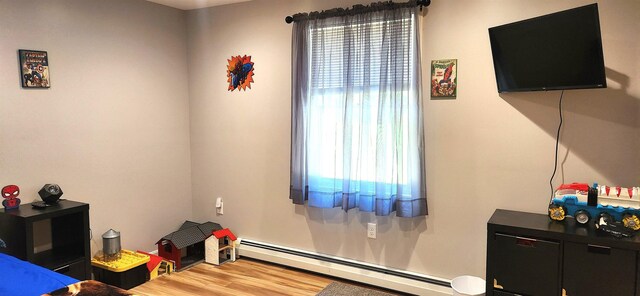 bedroom featuring baseboard heating, multiple windows, and hardwood / wood-style flooring