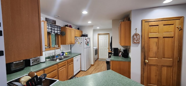 kitchen with washer and clothes dryer, white appliances, sink, and light hardwood / wood-style flooring