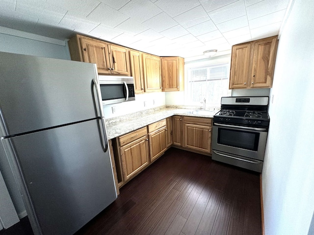 kitchen featuring light stone counters, sink, appliances with stainless steel finishes, and dark wood-type flooring