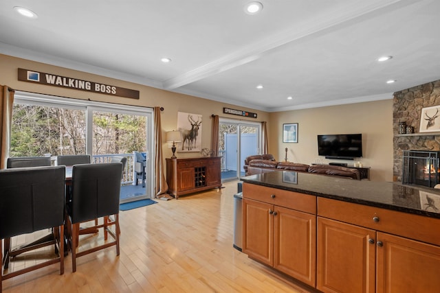 kitchen featuring dark stone countertops, a fireplace, plenty of natural light, and light hardwood / wood-style floors