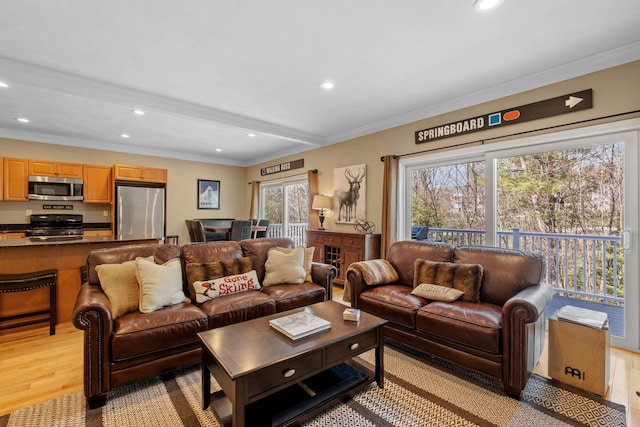 living room with beam ceiling, ornamental molding, and light hardwood / wood-style flooring