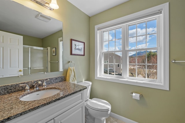 bathroom featuring vanity, toilet, and a shower with door