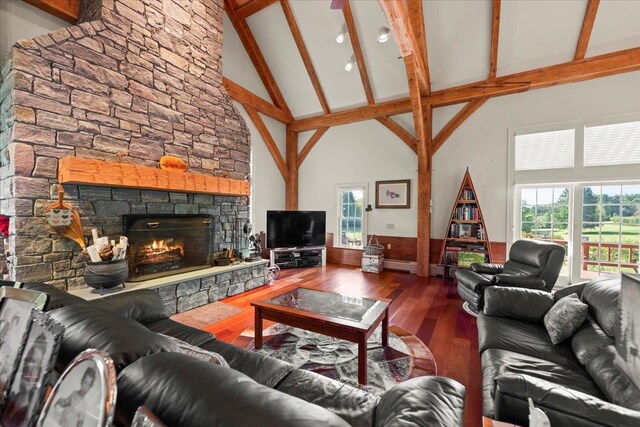 living room featuring a stone fireplace, beam ceiling, high vaulted ceiling, and hardwood / wood-style flooring