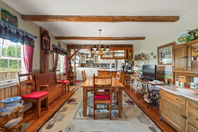 dining space featuring light hardwood / wood-style floors, a chandelier, and beamed ceiling