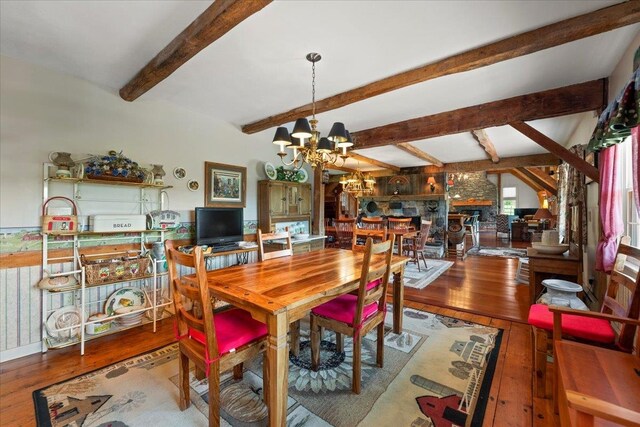 dining space featuring an inviting chandelier, beamed ceiling, and hardwood / wood-style floors