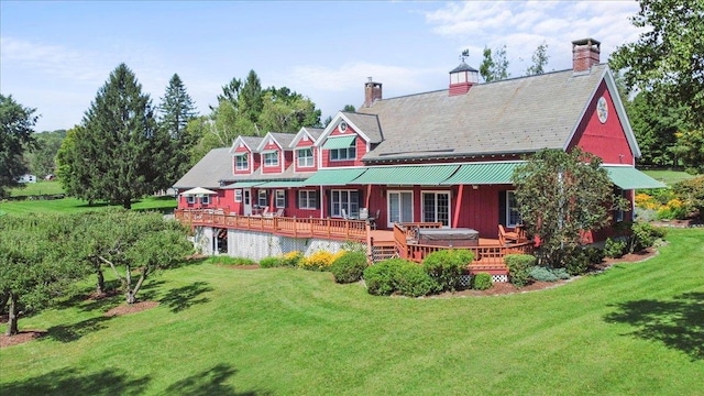 back of property featuring a wooden deck and a yard