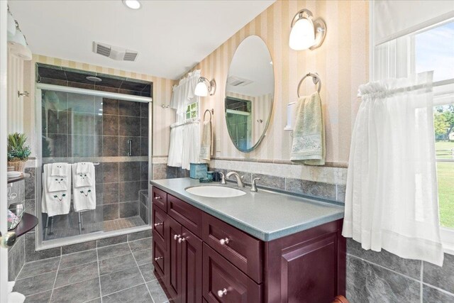 bathroom with walk in shower, tile walls, tile patterned flooring, and vanity