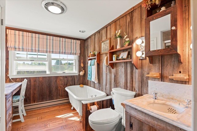 bathroom with vanity, wood walls, wood-type flooring, a tub to relax in, and toilet