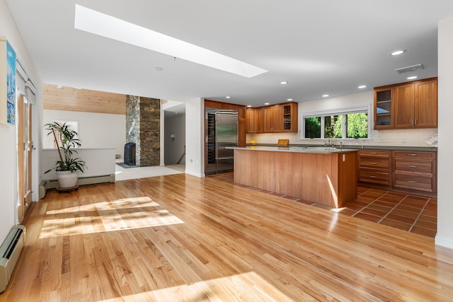 kitchen featuring light wood-type flooring, a kitchen island, a breakfast bar, a baseboard heating unit, and a skylight