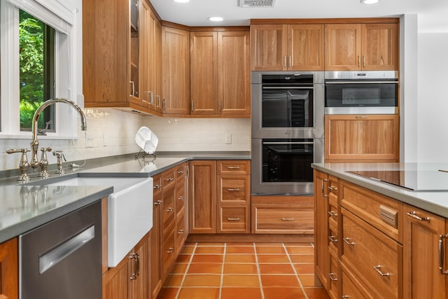 kitchen featuring sink, appliances with stainless steel finishes, backsplash, and light tile patterned floors