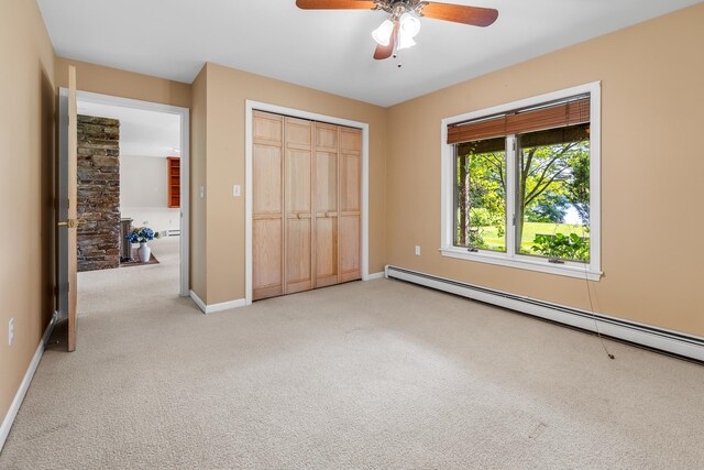 unfurnished bedroom featuring ceiling fan, baseboard heating, a closet, and carpet