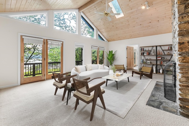 carpeted living room featuring ceiling fan, beamed ceiling, a skylight, high vaulted ceiling, and wooden ceiling