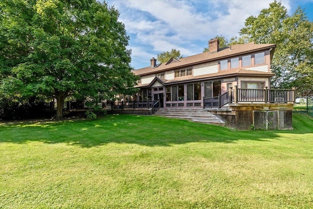 rear view of house with a wooden deck, a sunroom, and a yard