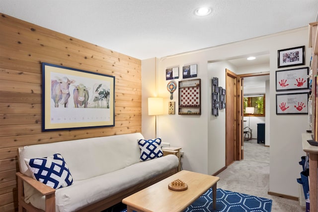 living room featuring wooden walls, light carpet, and a textured ceiling