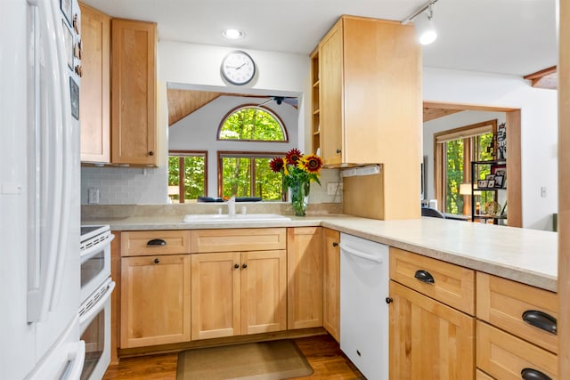 kitchen featuring white appliances, light brown cabinets, sink, hardwood / wood-style flooring, and kitchen peninsula