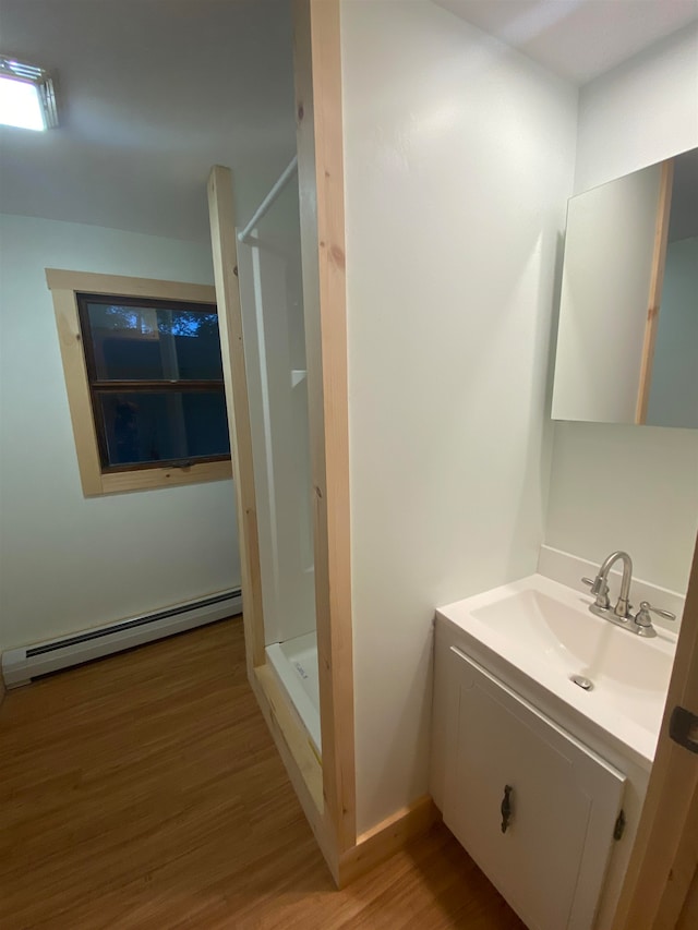 bathroom featuring walk in shower, vanity, hardwood / wood-style floors, and a baseboard heating unit