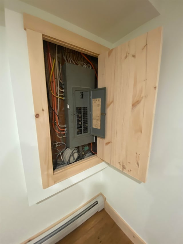 utility room with electric panel and a baseboard radiator