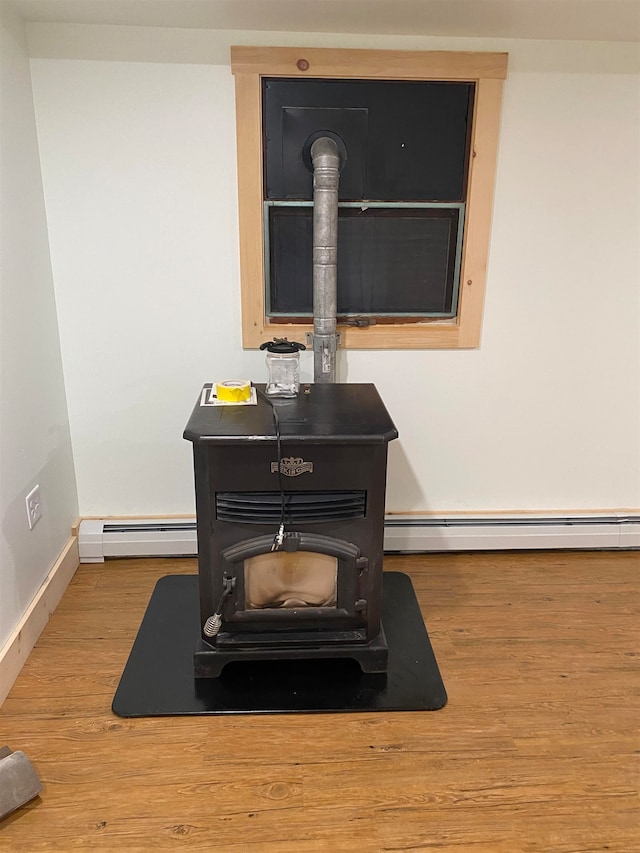 room details with hardwood / wood-style flooring, a wood stove, and a baseboard radiator