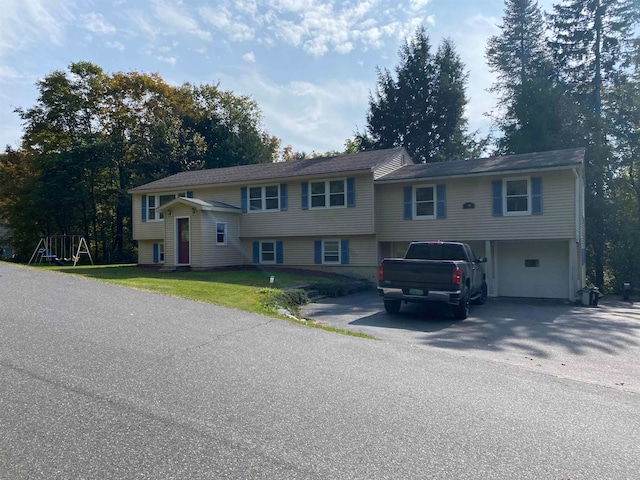 split foyer home with a garage, a playground, and a front lawn