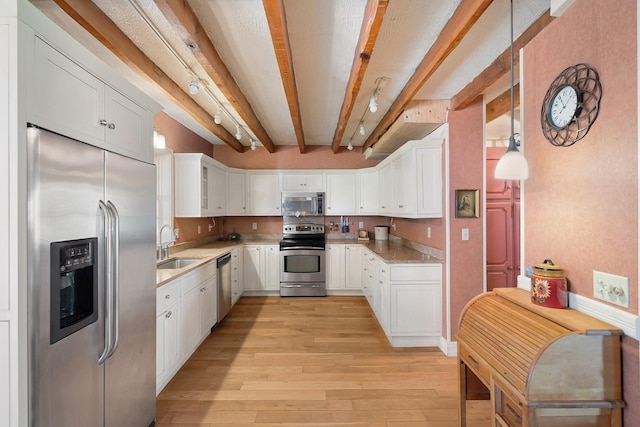 kitchen with pendant lighting, beamed ceiling, appliances with stainless steel finishes, and white cabinetry