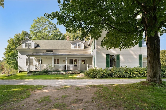 new england style home featuring a front yard and covered porch