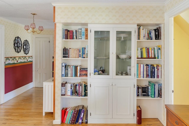 interior space with an inviting chandelier, light wood-type flooring, and ornamental molding