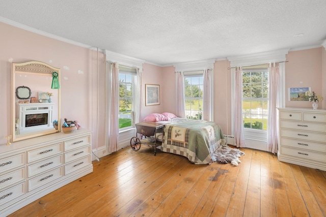 bedroom with a textured ceiling, light hardwood / wood-style flooring, and multiple windows