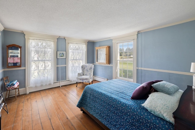 bedroom featuring hardwood / wood-style flooring, a baseboard radiator, ornamental molding, and a textured ceiling