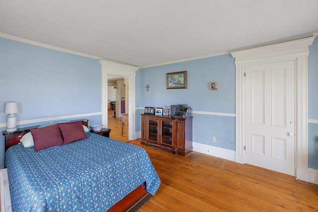 bedroom with a textured ceiling, crown molding, and hardwood / wood-style flooring