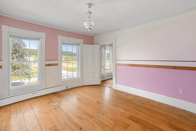 spare room with light wood-type flooring, baseboard heating, and crown molding