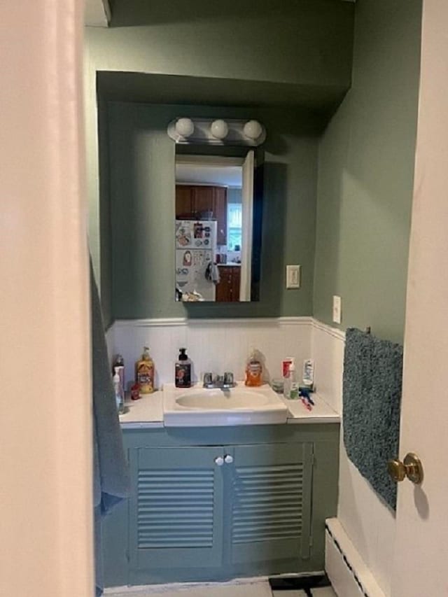 bathroom with vanity, a baseboard heating unit, and decorative backsplash