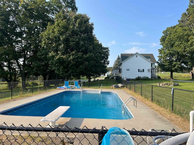 view of pool featuring a lawn and a diving board