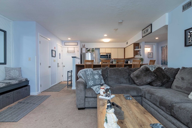 living room with recessed lighting, light colored carpet, visible vents, and a textured ceiling